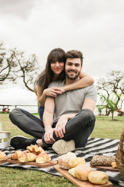 Retrato de la joven pareja sonriente en picnic en el parque