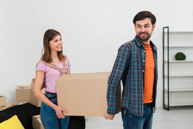 Retrato de una joven pareja sonriente sosteniendo una caja de cartón en movimiento