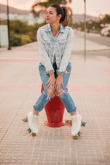 Retrato de una joven patinadora sentada en la acera