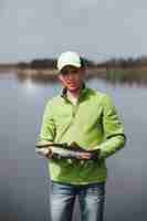 Foto gratuita retrato de un joven pescador con pescado fresco capturado