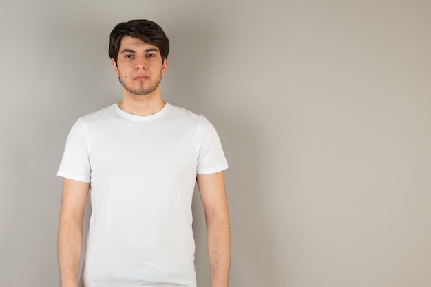 Foto gratuita retrato de un joven de pie contra el gris.