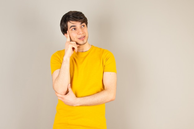 Retrato de un joven de pie y posando contra el gris.