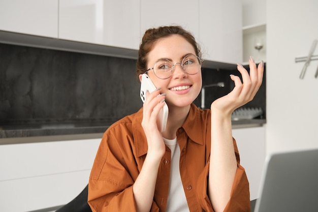 Foto gratuita retrato de una joven propietaria de un negocio que trabaja desde casa haciendo una llamada telefónica sentada