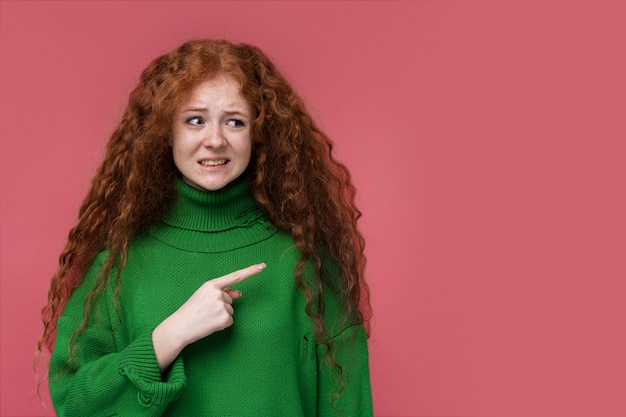 Foto gratuita retrato de una joven que parece confundida y apunta a la izquierda