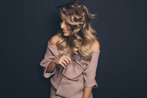 Retrato de una joven rubia hermosa con gafas de moda y ropa casual y posando sobre fondo negro