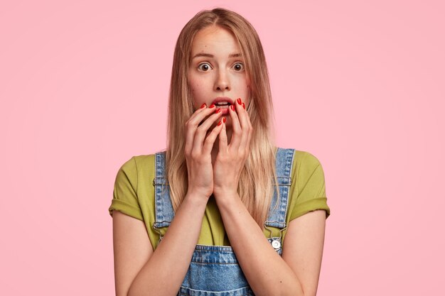 Retrato de joven rubia vistiendo overoles de mezclilla