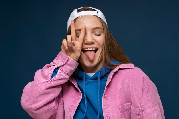 Retrato de una joven sacando la lengua y mostrando el signo de la paz
