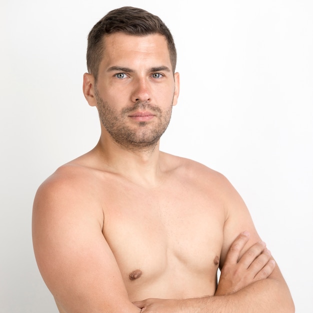 Retrato de joven serio con el brazo cruzado sobre fondo blanco.