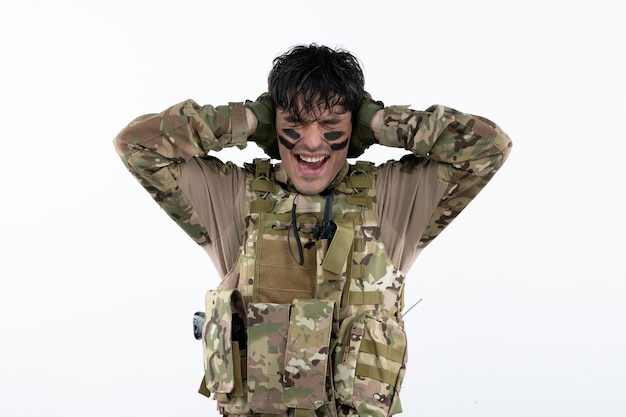 Foto gratuita retrato de joven soldado en camuflaje celebrando la victoria pared blanca