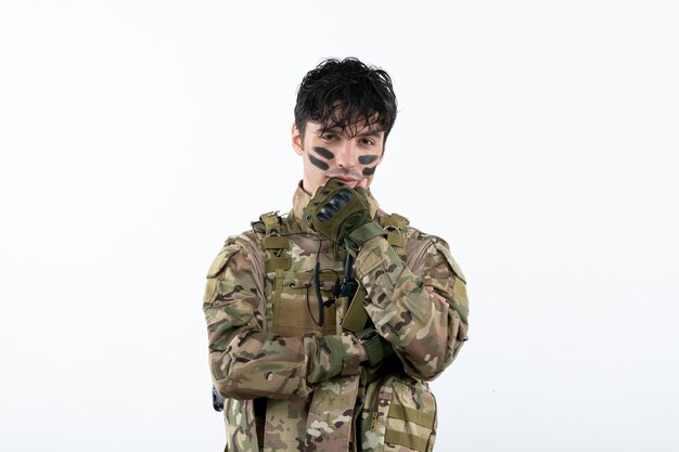 Retrato de joven soldado de camuflaje en la pared blanca