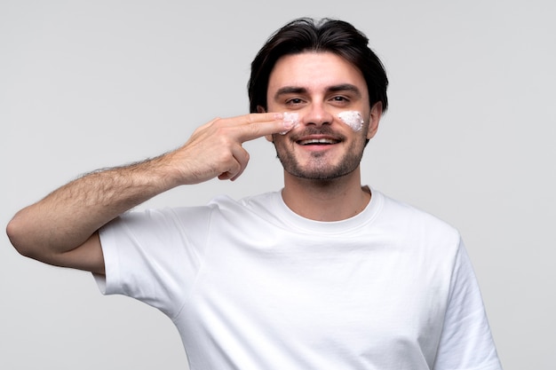 retrato, de, un, joven, sonriente, y, aplicación, humectante, en, el suyo, cara