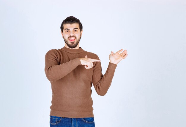 Retrato de un joven sonriente apuntando a su palma. Foto de alta calidad