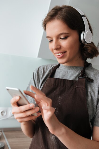 Retrato de una joven sonriente en auriculares con delantal