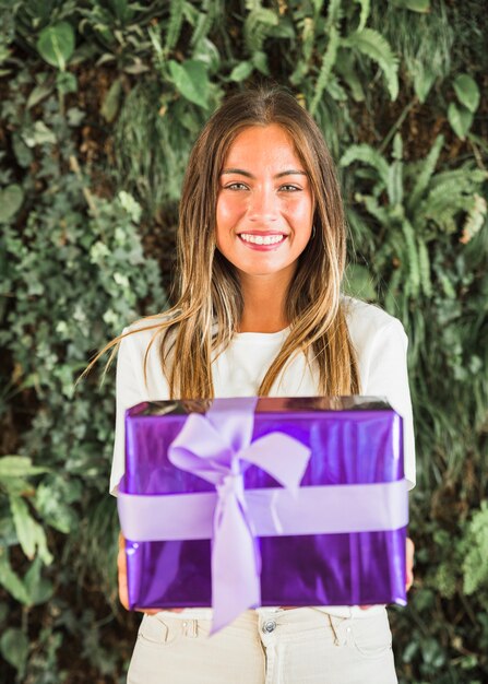 Retrato de una joven sonriente con caja de regalo púrpura