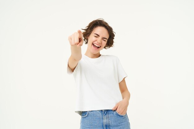 Foto gratuita retrato de una joven sonriente emocionada apuntando con el dedo a la cámara invitándote a felicitar