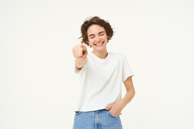 Foto gratuita retrato de una joven sonriente emocionada apuntando con el dedo a la cámara invitándote a felicitar