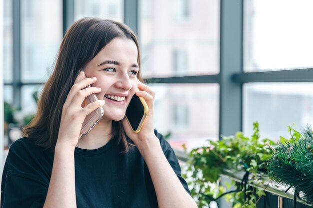 Retrato de una joven sonriente hablando por dos teléfonos