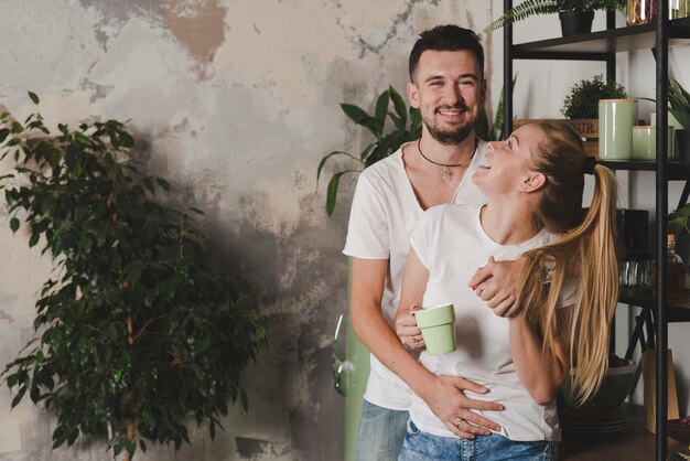 Retrato de joven sonriente pareja de pie en la cocina