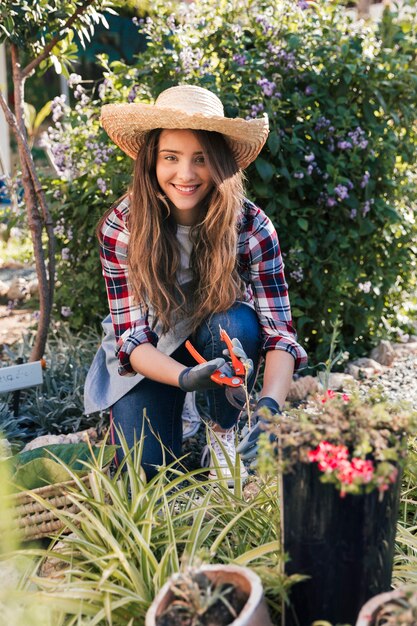 Retrato de una joven sonriente podando las plantas mirando a cámara