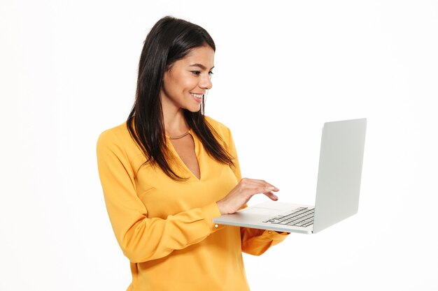 Retrato de una joven sonriente que trabaja en la computadora portátil