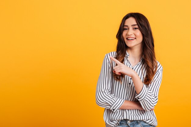 Retrato de una joven sonriente señalando con el dedo