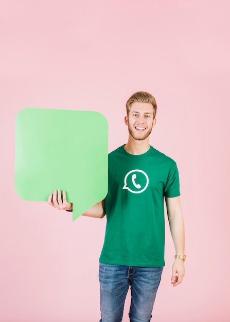 Retrato de un joven sonriente sosteniendo el bocadillo de diálogo verde vacío