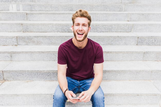 Retrato de un joven sonriente con teléfono inteligente