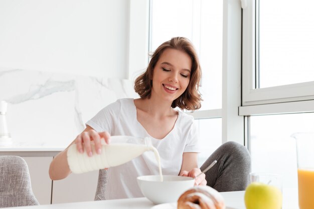 Retrato de una joven sonriente vertiendo leche