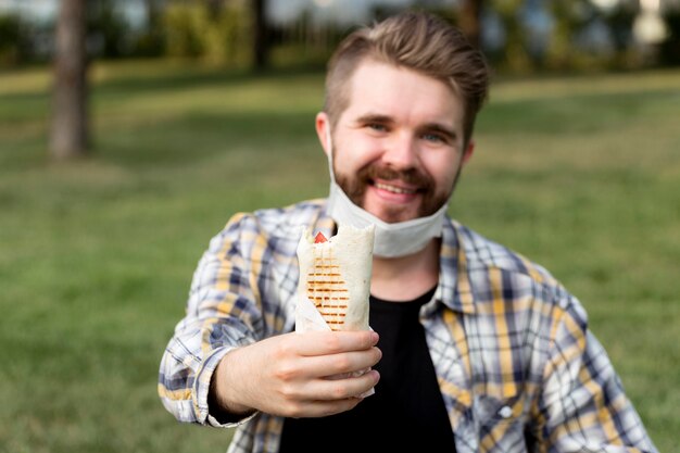 Retrato de joven sosteniendo sabroso kebab