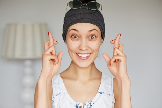 Retrato de joven supersticiosa feliz cruzando los dedos de cerca