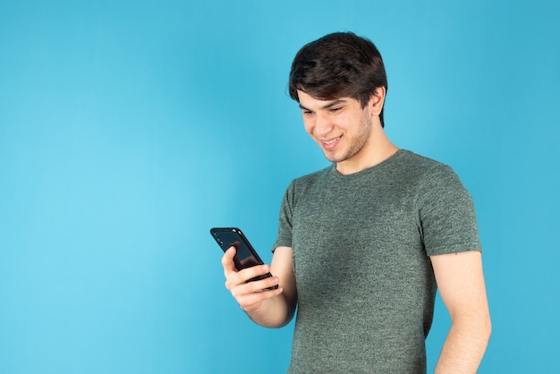 Retrato de un joven con un teléfono móvil contra el azul.