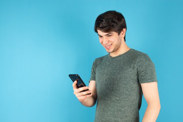 Retrato de un joven con un teléfono móvil contra el azul.