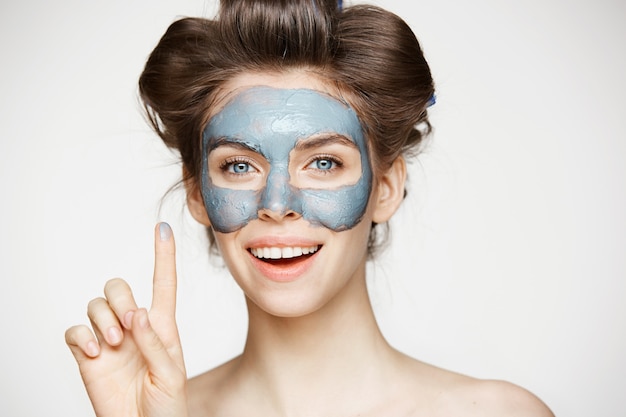 Retrato de joven tierna en Rizadores para el cabello y máscara facial sonriendo. Concepto de belleza y cuidado de la piel.