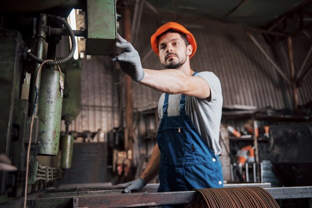 Retrato de un joven trabajador con un casco en una gran fábrica de reciclaje de residuos.