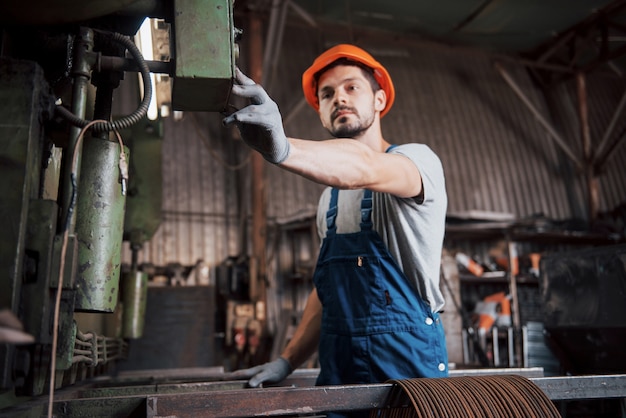 Retrato de un joven trabajador con un casco en una gran fábrica de reciclaje de residuos.