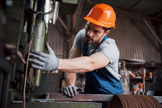 Retrato de un joven trabajador con un casco en una gran fábrica de reciclaje de residuos.