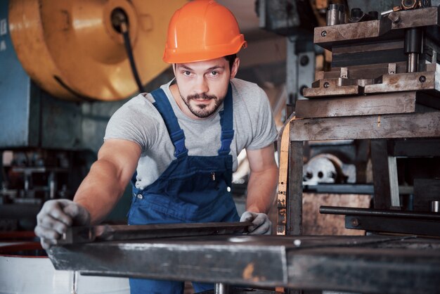 Retrato de un joven trabajador con un casco en una gran fábrica de reciclaje de residuos.