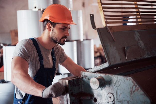 Retrato de un joven trabajador con un casco en una gran fábrica de reciclaje de residuos.