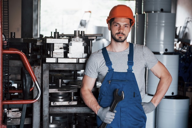 Retrato de un joven trabajador con un casco en una gran planta metalúrgica.