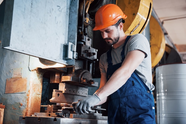 Retrato de un joven trabajador con un casco en una gran planta metalúrgica.