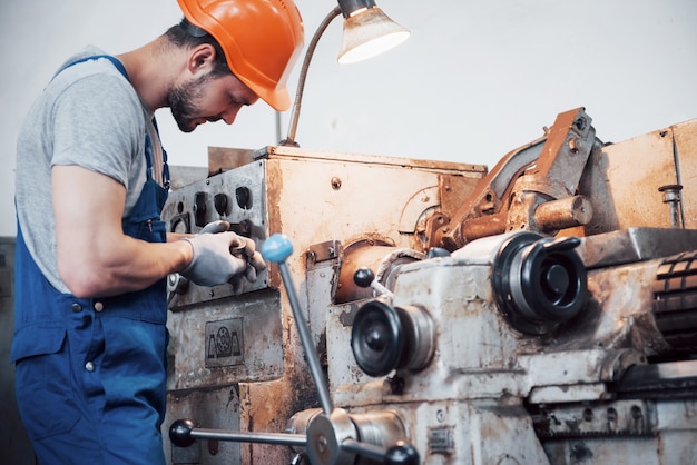 Retrato de un joven trabajador con un casco en una gran planta metalúrgica.