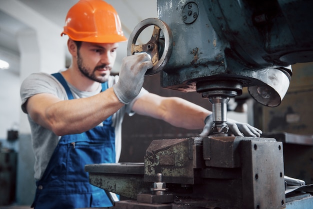 Retrato de un joven trabajador con un casco en una gran planta metalúrgica.