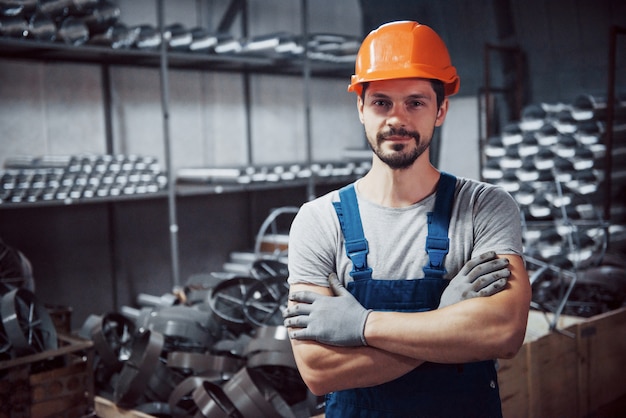 Retrato de un joven trabajador con un casco en una gran planta metalúrgica.