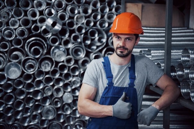 Retrato de un joven trabajador con un casco en una gran planta metalúrgica.