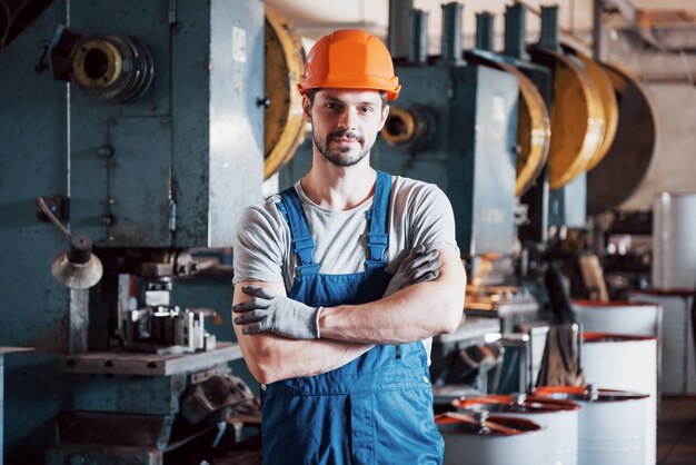 Retrato de un joven trabajador con un casco en una gran planta metalúrgica.