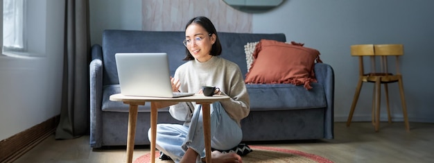 Foto gratuita retrato de una joven trabajadora coreana que estudia a distancia en línea hablando con un video chat con una computadora portátil