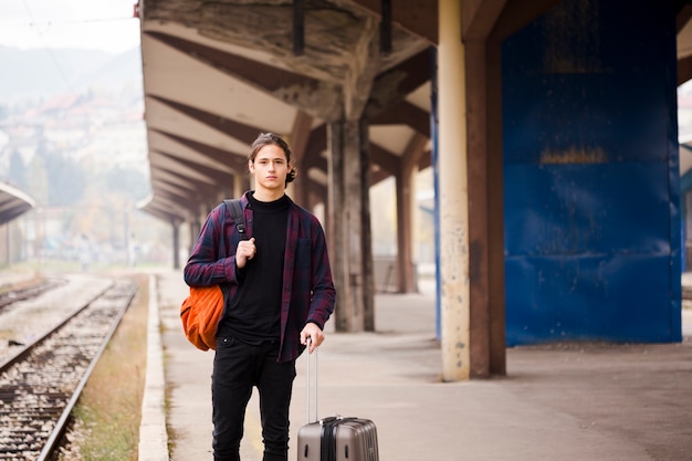 Retrato de joven turista esperando un tren