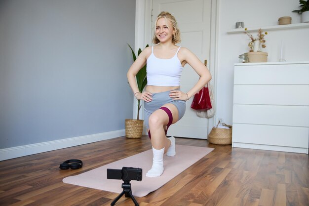 Foto gratuita retrato de una joven vlogger atlética haciendo un video sobre una instructora de fitness de entrenamiento en casa