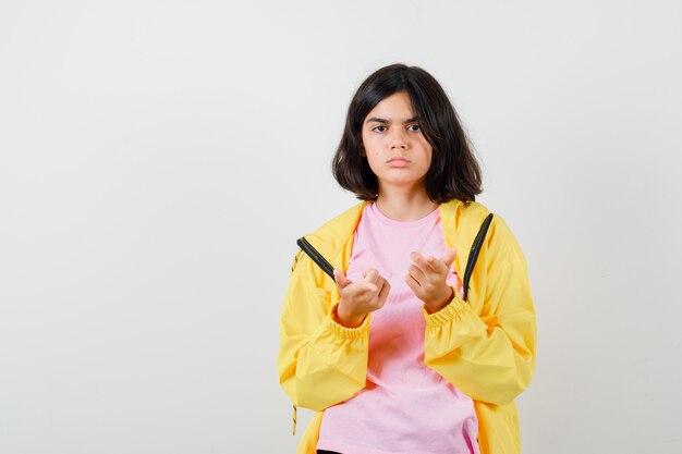 Retrato de jovencita apuntando en camiseta, chaqueta y mirando seria vista frontal