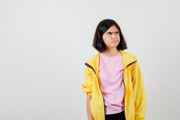 Retrato de jovencita mirando a otro lado en camiseta, chaqueta y mirando molesto vista frontal